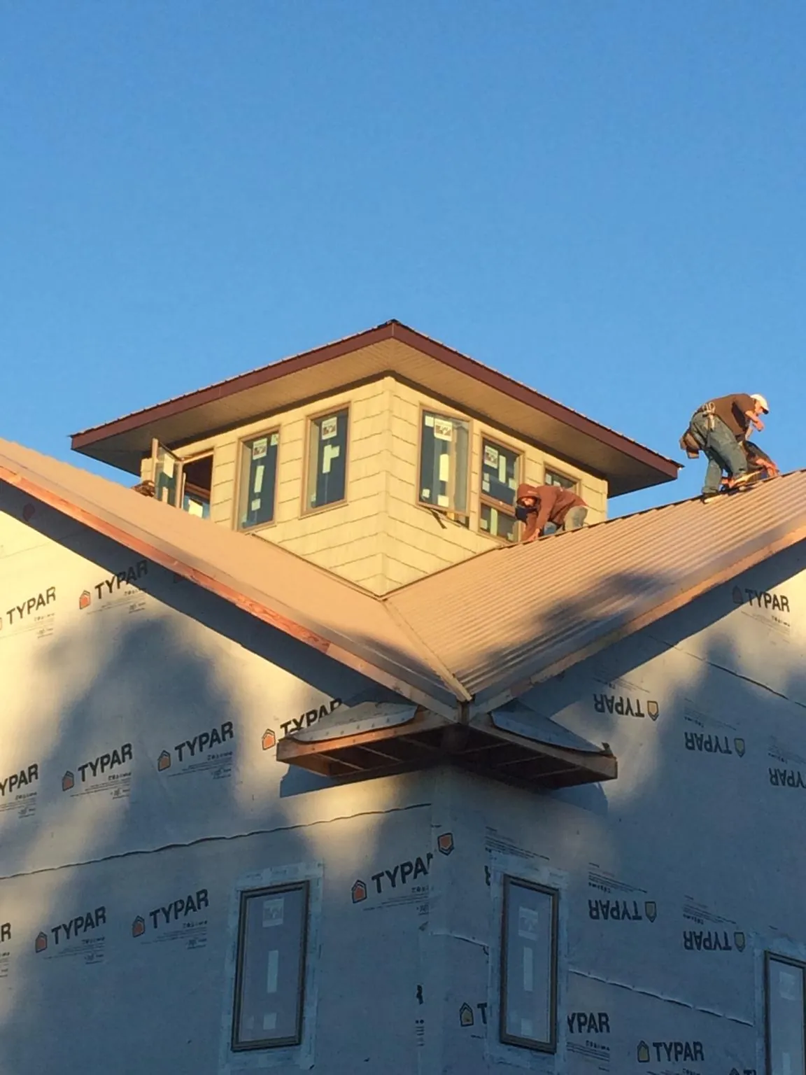 Roofers working around a rooftop cupola on a new metal roof at sunset — Roof Waterproofing in Roanoke by Roofing Brothers